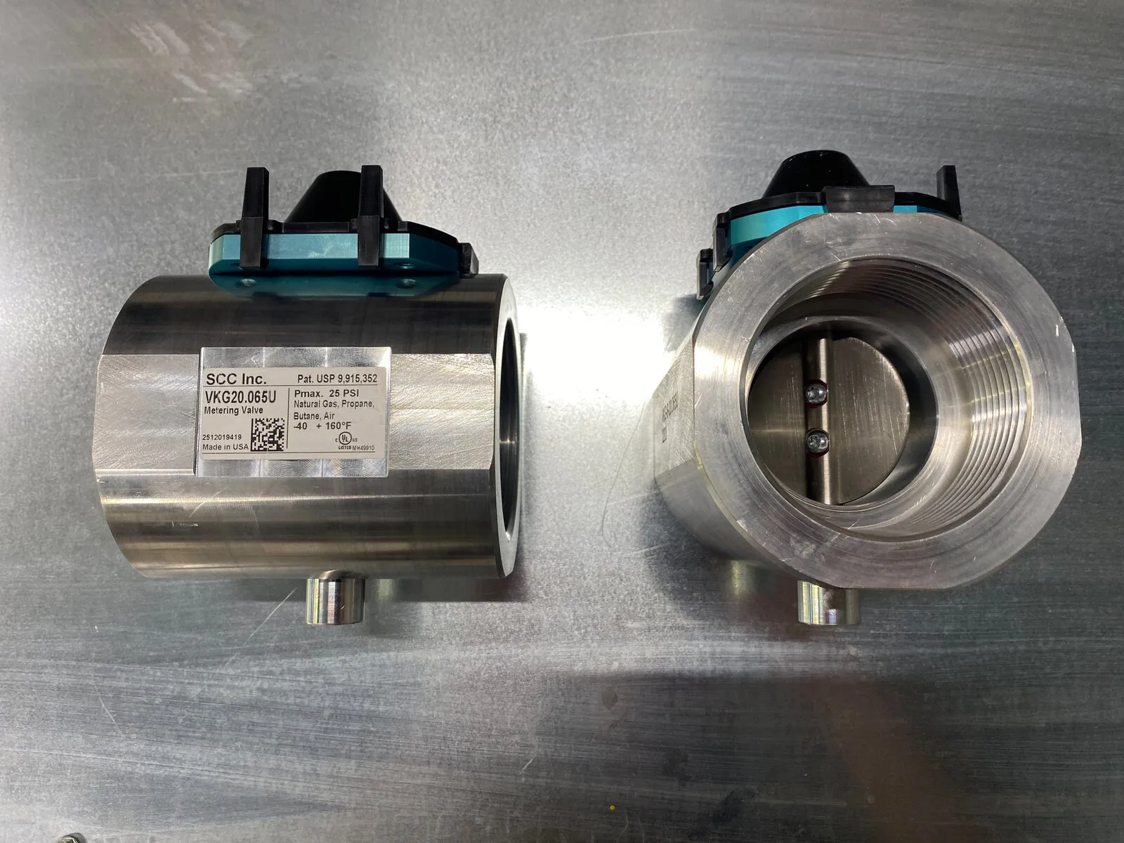 Deux vannes de dosage de gaz en acier inoxydable sur l’établi, l’une tournée pour montrer le disque dans son alésage