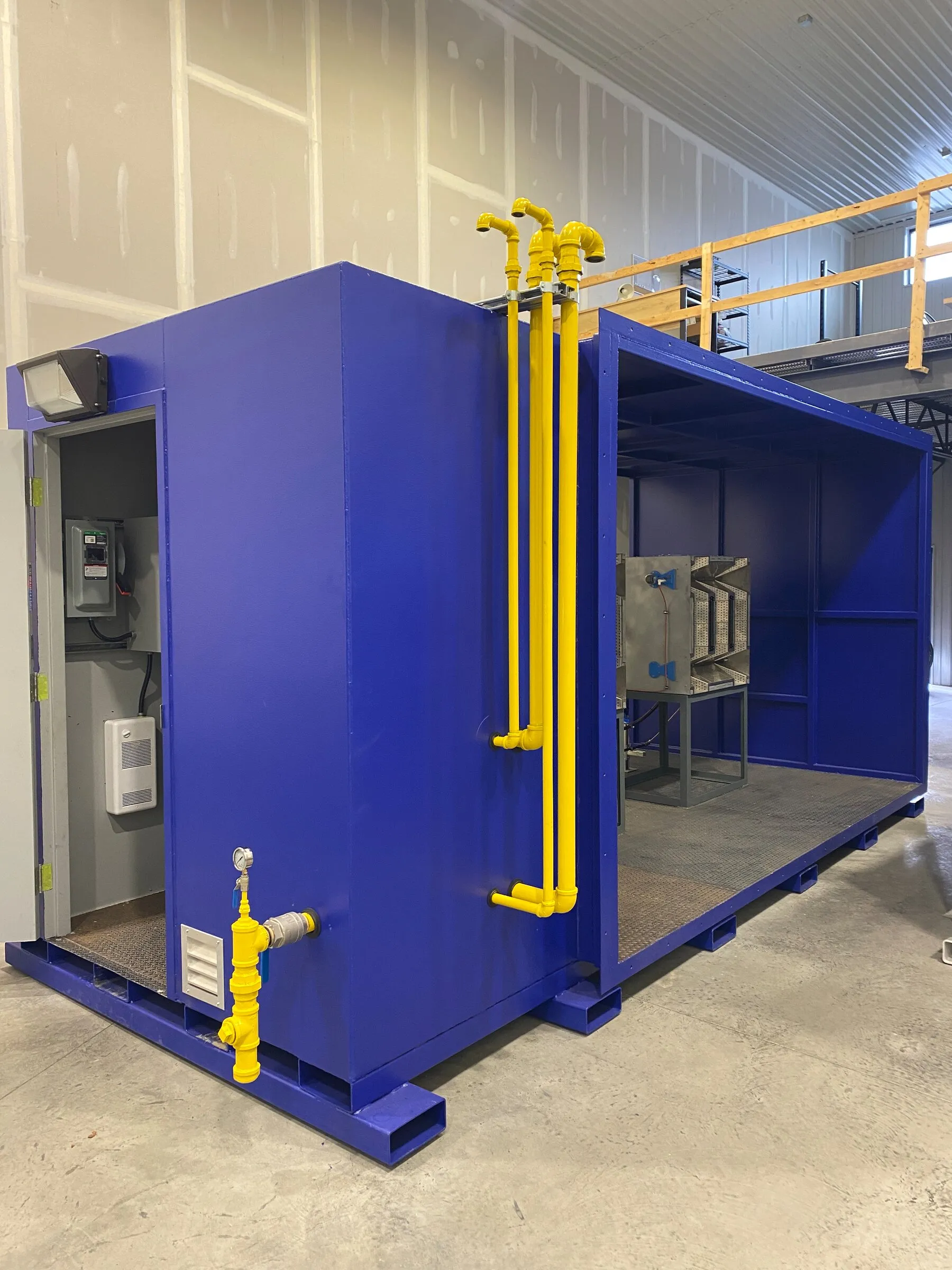 Réchauffeur d’air minier avec ses colonnes de train de gaz et son armoire de commande, l’extrémité ouverte laissant voir l’ensemble brûleur